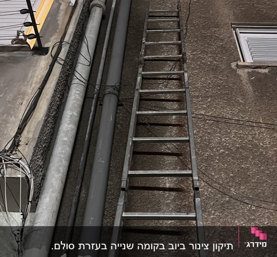סולם מתכת צמוד לקיר עם צינורות חשמל